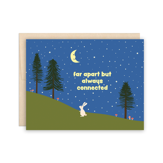 Greeting card with a rabbit, trees, and moon on a blue night sky background.